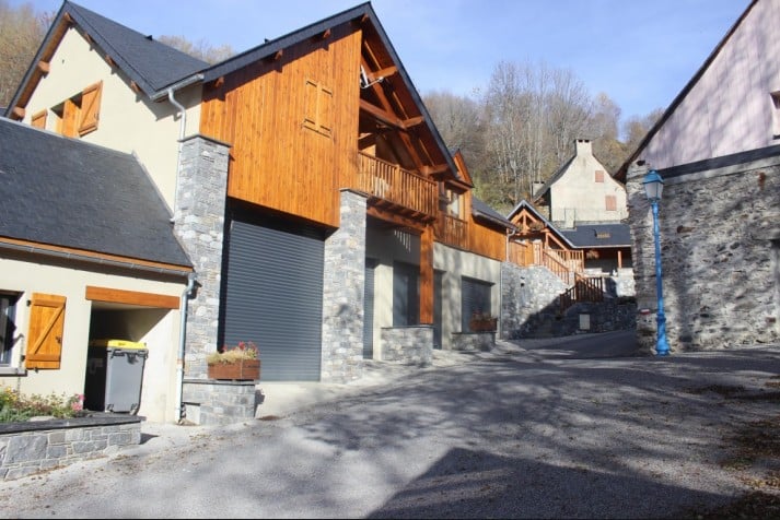 Chalets de Montagne Modernes en Bois et Pierre Taillée Chalets modernes en pierre et bois bordant une rue en pente dans un village de montagne ensoleillé.