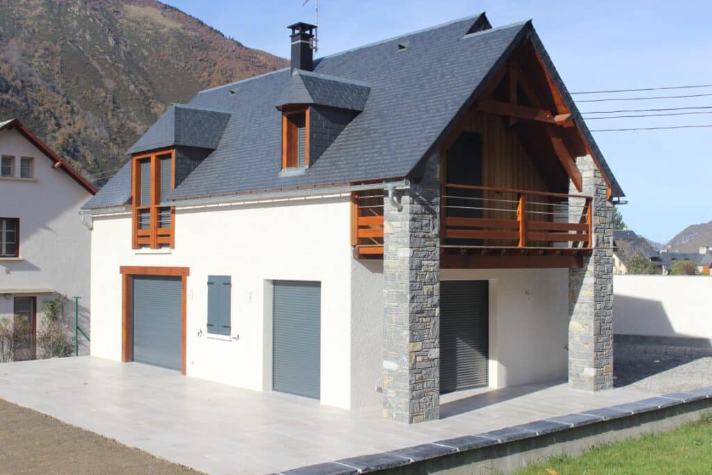 Chalet de Montagne Moderne : Toit en Ardoise et Balcon Bois Maison de montagne avec toit en ardoise, balcon en bois et piliers en pierre dans un cadre alpin paisible.