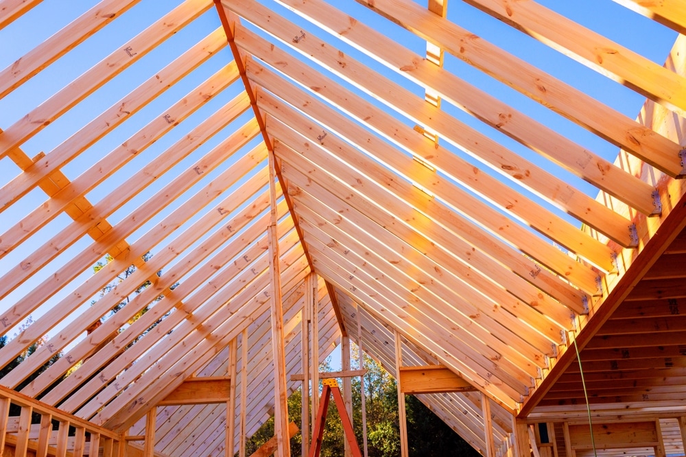 Construction de Charpente en Bois pour Toiture Maison Charpente en bois d'un toit en cours de construction sous un ciel bleu dégagé.
