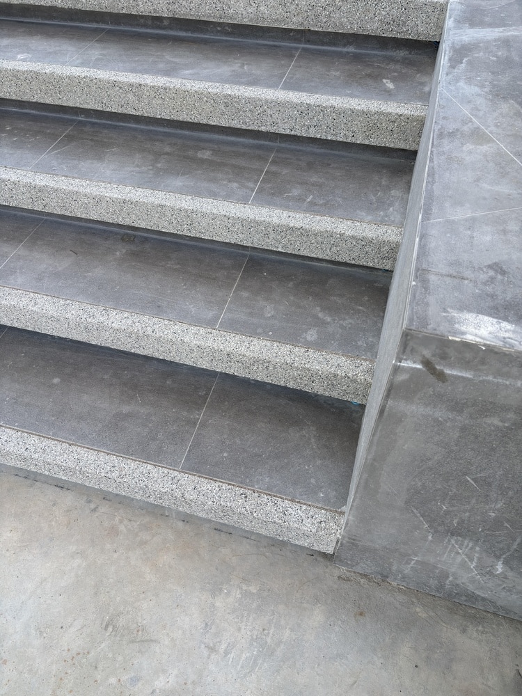 Escalier Carrelage Gris et Nez de Marche Sécurisé Escalier moderne avec carrelage gris et nez de marche antidérapant en pierre mouchetée claire.