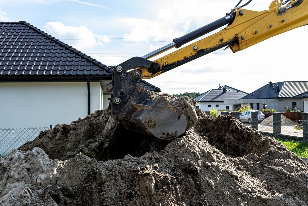 Travaux d'excavation sur un chantier résidentiel Bras d'excavatrice jaune déplaçant de la terre sur un chantier de construction résidentielle.