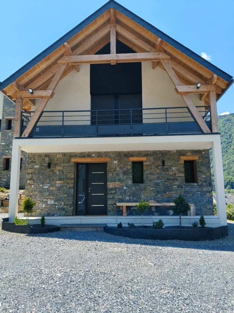 Chalet moderne avec pignon bois, façade en pierre, porte noire et balcon numéro 8.
